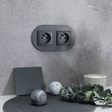 Prises Graphite Mat NuanceLumi sur un mur minéral contemporain